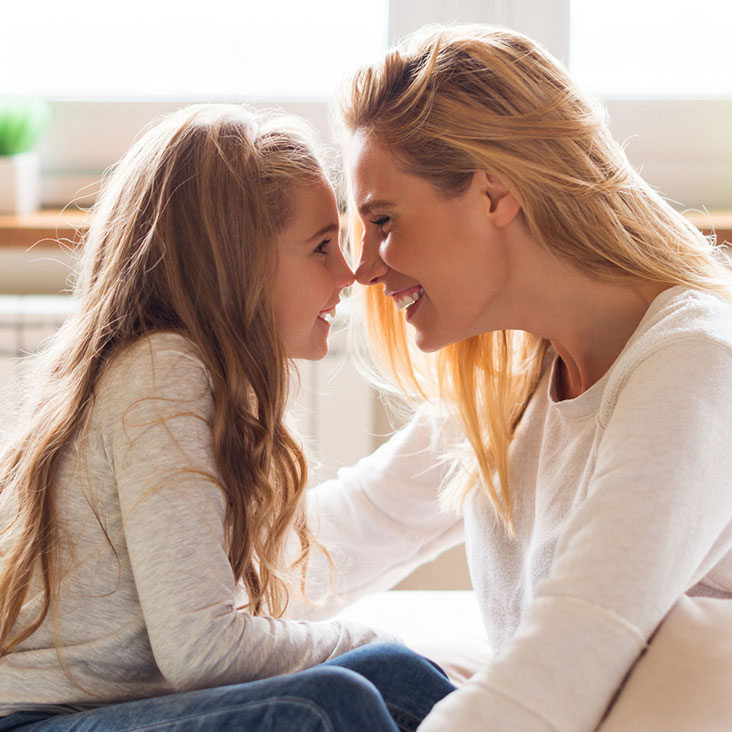 Mother and daughter cuddling in living room