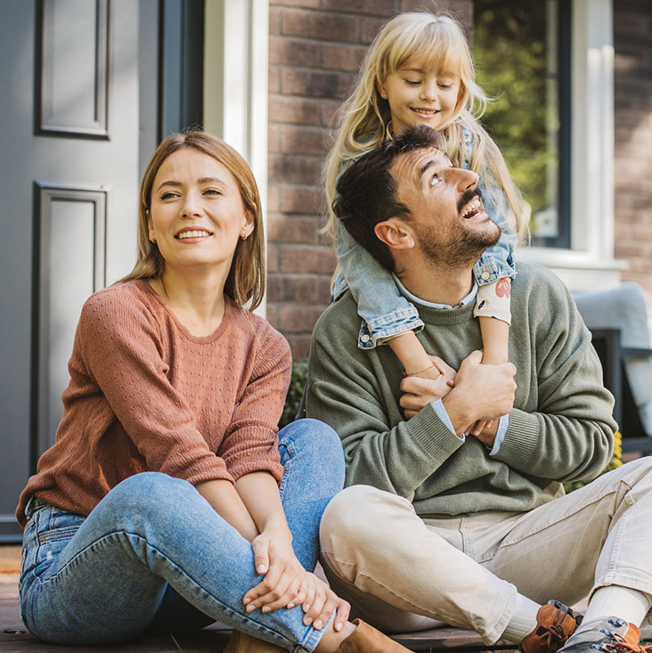 Young family sitting on front porch