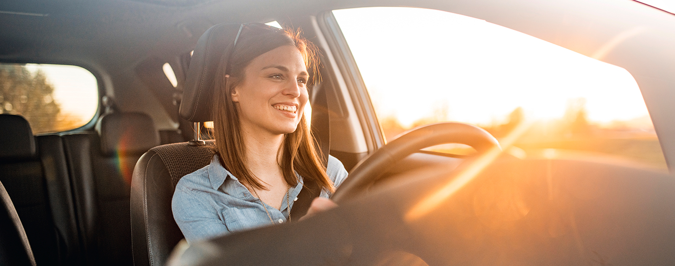 Close up of a young woman driving a car in the sun